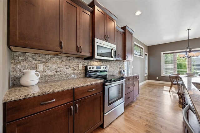 kitchen featuring appliances with stainless steel finishes, baseboards, decorative backsplash, a chandelier, and light wood-style floors