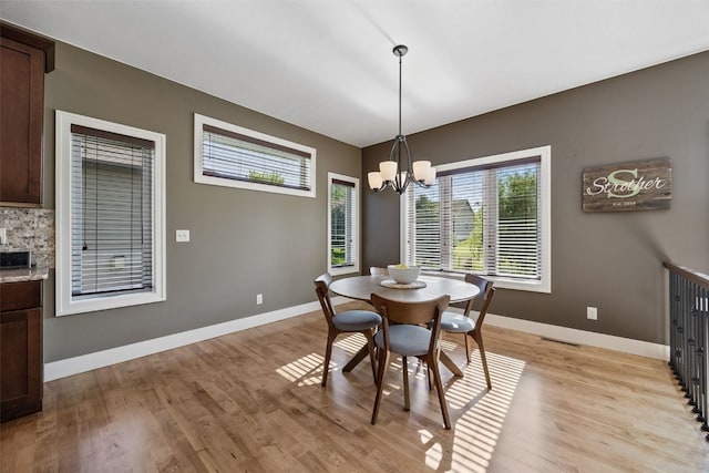 dining area featuring light wood-style floors, baseboards, and a chandelier