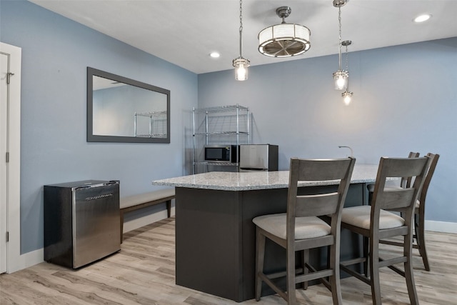 kitchen with appliances with stainless steel finishes, light stone countertops, light wood-style flooring, baseboards, and recessed lighting