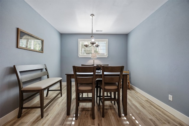 dining room with a chandelier, baseboards, and light wood-style floors