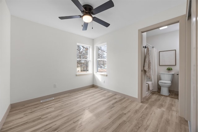 841 S 7th St, Iowa City, IA 52240 - unfurnished bedroom with light wood finished floors, baseboards, connected bathroom, and ceiling fan