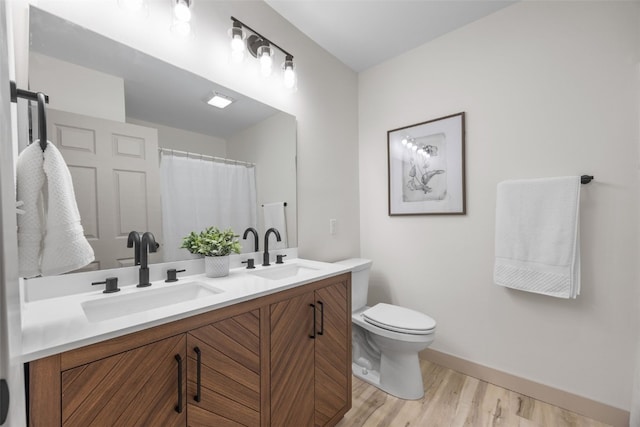 841 S 7th St, Iowa City, IA 52240 - bathroom featuring toilet, wood finished floors, baseboards, and double vanity