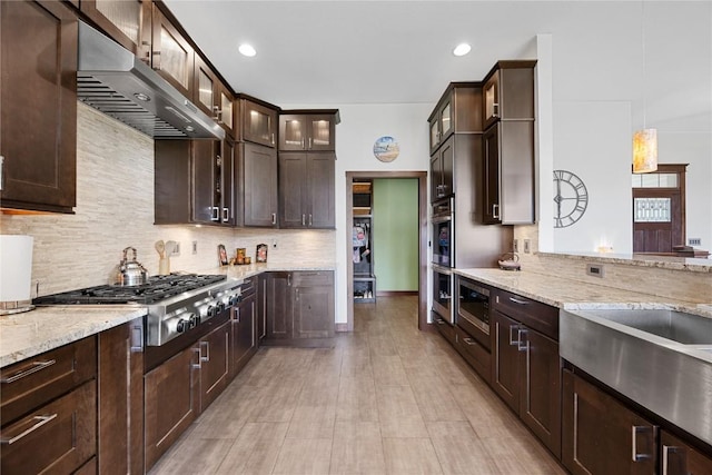 302 6th St NE, Mount Vernon, IA 52314 - kitchen featuring appliances with stainless steel finishes, exhaust hood, dark brown cabinetry, light stone counters, and recessed lighting