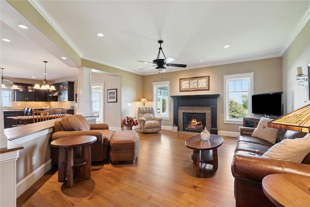 1443 69th St, Keystone, IA 52249 - living area featuring light wood-type flooring, a ceiling fan, a warm lit fireplace, recessed lighting, and ornate columns