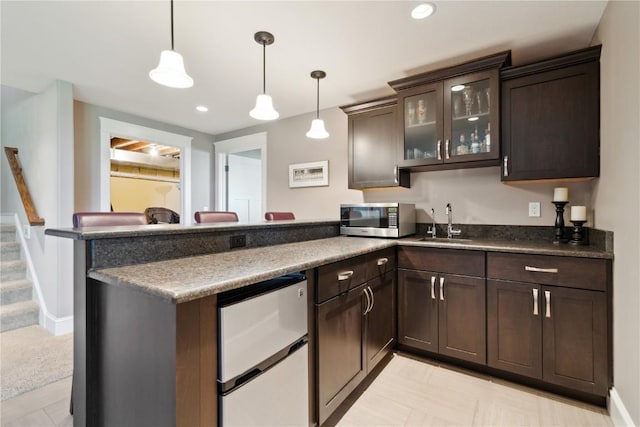 1443 69th St, Keystone, IA 52249 - kitchen featuring stainless steel microwave, a peninsula, a sink, freestanding refrigerator, and dark brown cabinetry