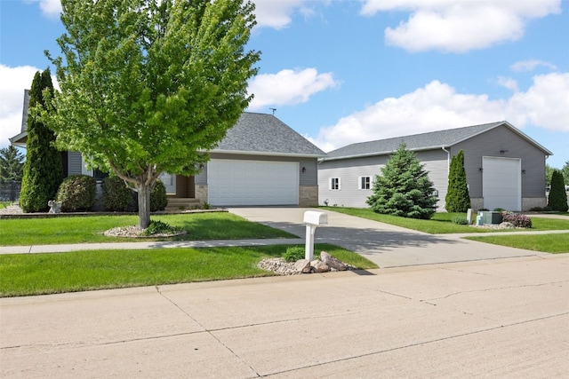 view of front of property with an attached garage, concrete driveway, a front yard, and central air condition unit
