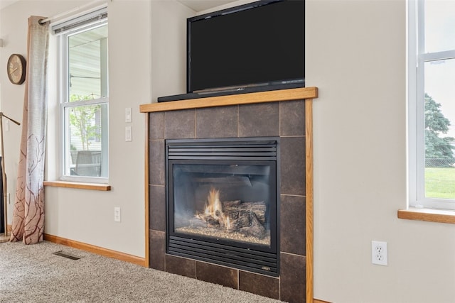 detailed view of carpet flooring, a tiled fireplace, and baseboards