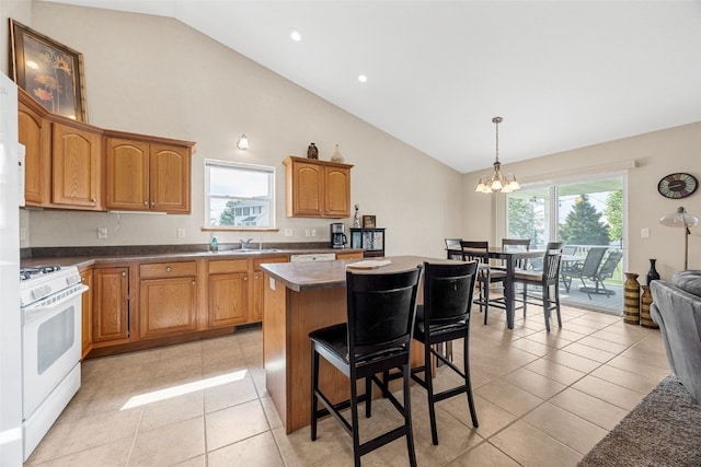 kitchen featuring gas range gas stove, a chandelier, a kitchen island, high vaulted ceiling, and dark countertops