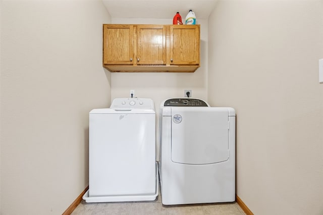 clothes washing area featuring washer and dryer, cabinet space, and baseboards