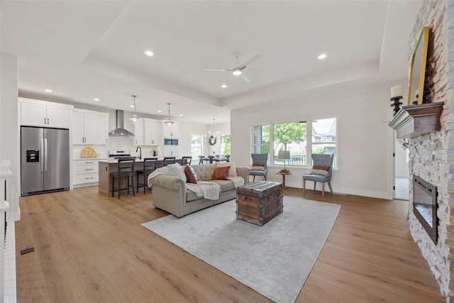 424 15th Ave SW, Mount Vernon, IA 52314 - living area featuring a tray ceiling, ceiling fan, a stone fireplace, light wood-style floors, and recessed lighting
