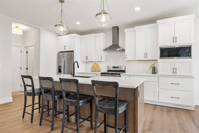 424 15th Ave SW, Mount Vernon, IA 52314 - kitchen featuring wall chimney range hood, appliances with stainless steel finishes, a sink, a kitchen island with sink, and decorative backsplash