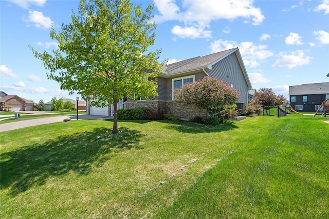 395 Carlyle Dr, North Liberty, IA 52317 - view of front of property with concrete driveway, a front lawn, a playground, and stone siding