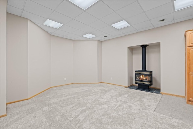 942 Evergreen Ct, Iowa City, IA 52245 - unfurnished living room featuring a wood stove, a paneled ceiling, carpet floors, and baseboards