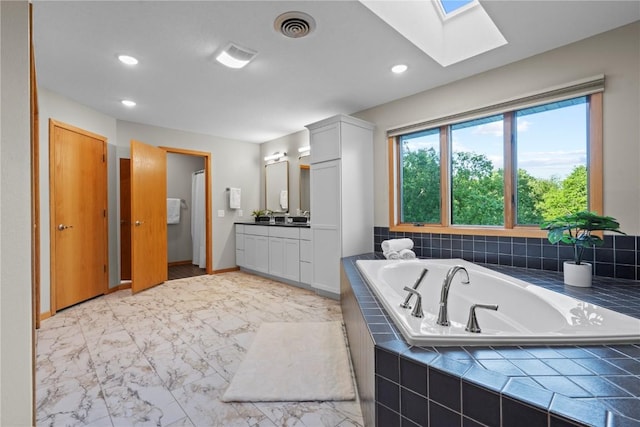 942 Evergreen Ct, Iowa City, IA 52245 - bathroom featuring a skylight, vanity, a garden tub, marble finish flooring, and recessed lighting
