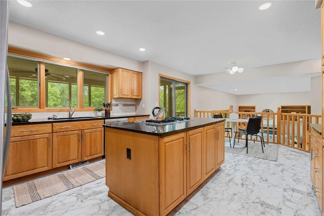 942 Evergreen Ct, Iowa City, IA 52245 - kitchen with a sink, light marble finish floors, stainless steel gas stovetop, dark countertops, and a center island