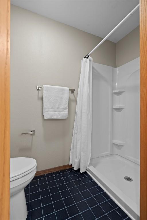 942 Evergreen Ct, Iowa City, IA 52245 - full bath featuring tile patterned floors, a stall shower, toilet, and baseboards
