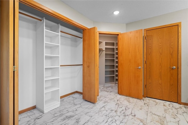 942 Evergreen Ct, Iowa City, IA 52245 - unfurnished bedroom featuring light marble finish flooring, baseboards, recessed lighting, a closet, and a walk in closet