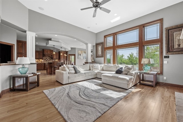 4355 Par Cir, Marion, IA 52302 - living room featuring ornate columns, ceiling fan, light wood finished floors, arched walkways, and a towering ceiling