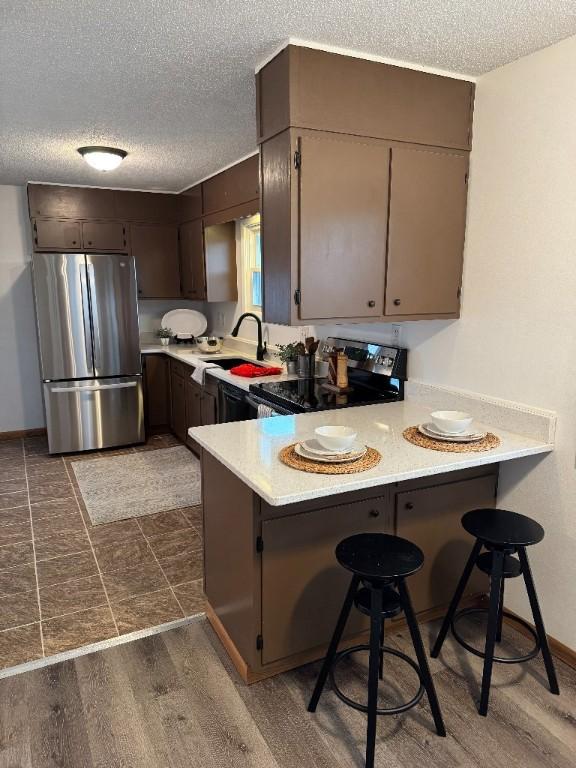 3105 Wilson Ave SW, Cedar Rapids, IA 52404 - kitchen with freestanding refrigerator, electric range oven, a textured ceiling, a peninsula, and light countertops