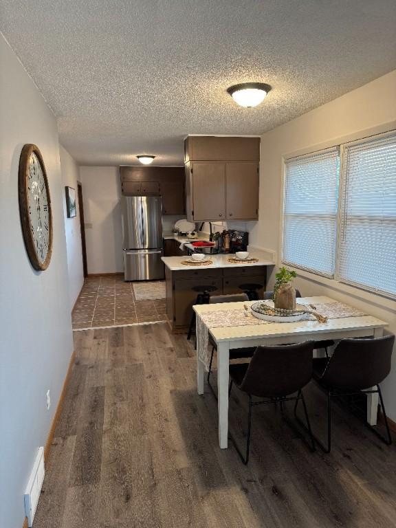 3105 Wilson Ave SW, Cedar Rapids, IA 52404 - kitchen with freestanding refrigerator, a textured ceiling, wood finished floors, a peninsula, and light countertops