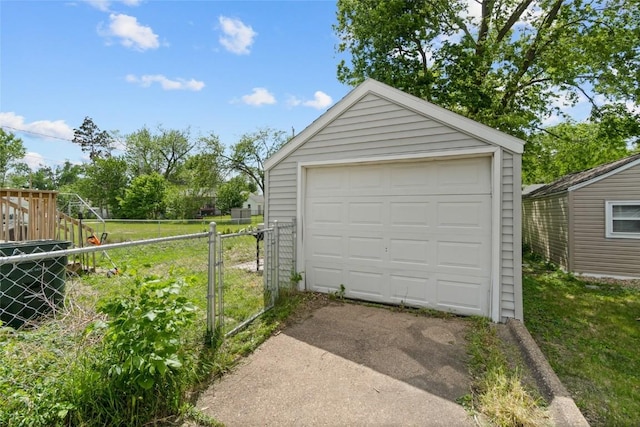 detached garage featuring concrete driveway, fence, and a gate