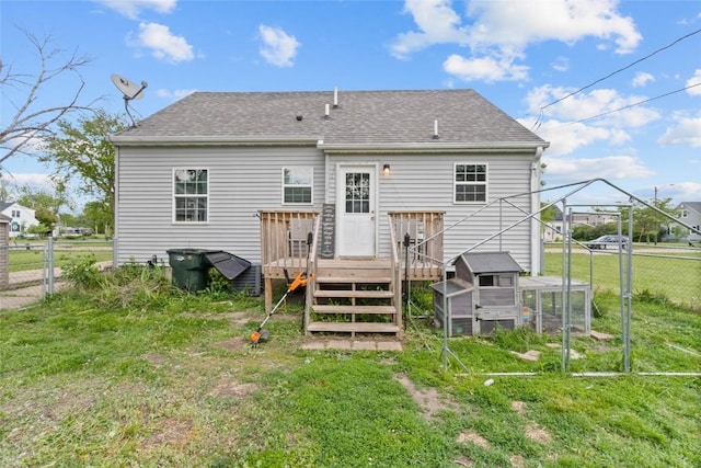back of house featuring exterior structure, a wooden deck, roof with shingles, and an outdoor structure
