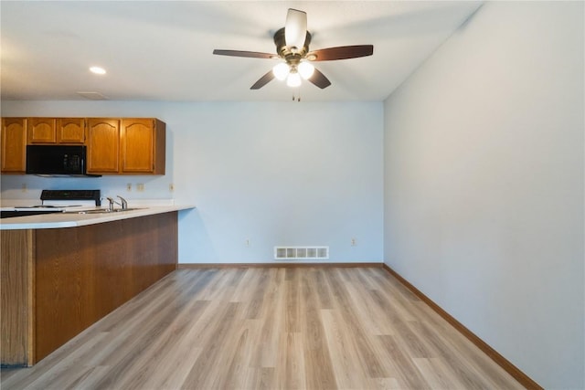 3035 English Glen Ct Unit D7, Marion, IA 52302 - kitchen with black microwave, electric range oven, brown cabinetry, baseboards, and light wood-style flooring