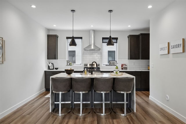 830 Newton Rd Unit 4, Iowa City, IA 52246 - kitchen featuring wall chimney exhaust hood, a sink, a breakfast bar, a center island with sink, and light countertops