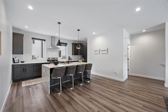 830 Newton Rd Unit 4, Iowa City, IA 52246 - kitchen with wall chimney exhaust hood, light countertops, backsplash, an island with sink, and recessed lighting