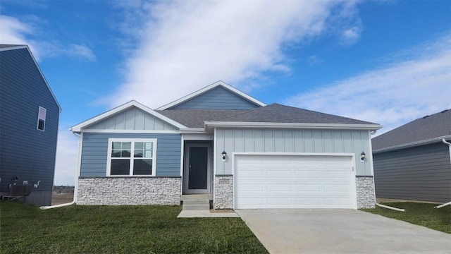705 E Goldfinch Dr, Tiffin, IA 52340 - view of front of home with stone siding, concrete driveway, board and batten siding, a garage, and a front yard