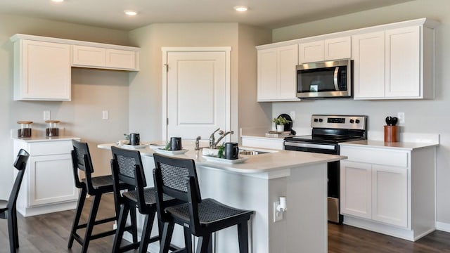 626 Maddie Ln, Tiffin, IA 52340 - kitchen featuring appliances with stainless steel finishes, a kitchen island with sink, recessed lighting, dark wood finished floors, and white cabinets
