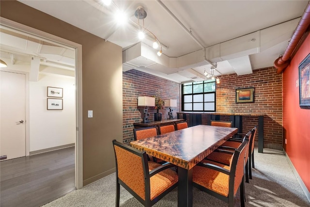 905 3rd St SE Unit 111, Cedar Rapids, IA 52401 - dining space featuring brick wall, baseboards, track lighting, and wood finished floors