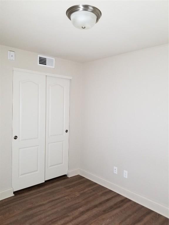 200 Grandview Ct Unit 204, Iowa City, IA 52246 - unfurnished bedroom with baseboards, a closet, and dark wood-type flooring