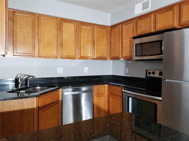 200 Grandview Ct Unit 204, Iowa City, IA 52246 - kitchen featuring stainless steel appliances, a sink, brown cabinetry, and dark stone counters