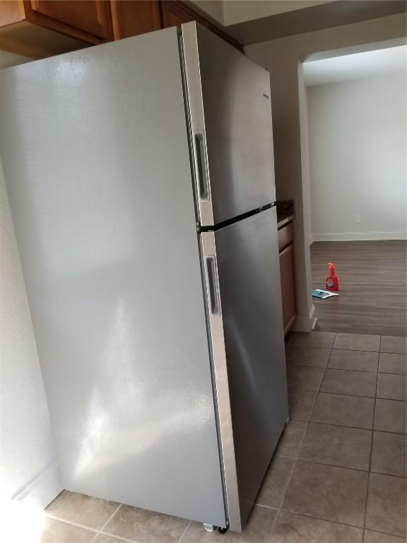 100 Granview Ct Unit 126, Iowa City, IA 52246 - kitchen with freestanding refrigerator, light tile patterned floors, baseboards, and brown cabinetry