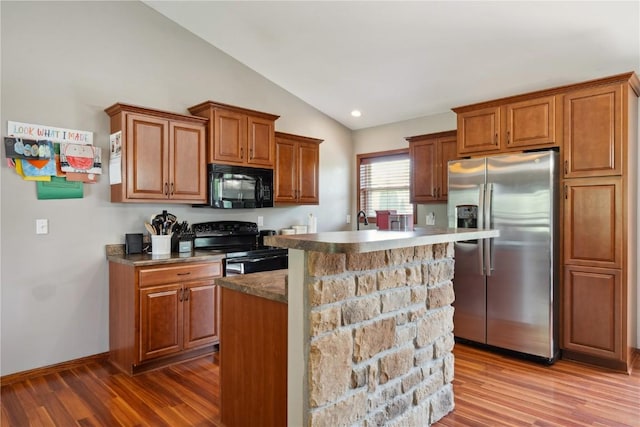 4708 Pueblo St SW, Cedar Rapids, IA 52404 - kitchen featuring black appliances, lofted ceiling, dark wood-style floors, brown cabinets, and a kitchen island