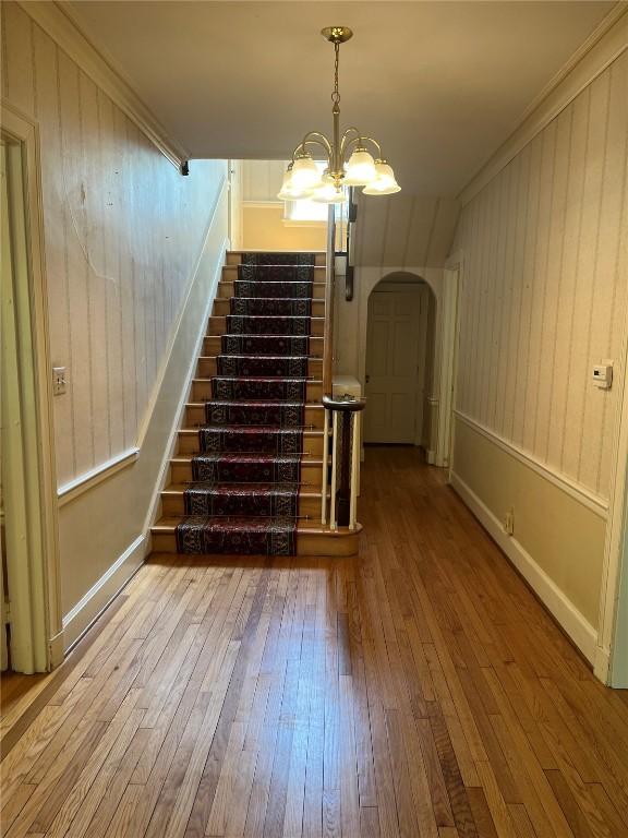 620 S Summit St, Iowa City, IA 52240 - stairs with wood-type flooring, arched walkways, a chandelier, baseboards, and crown molding
