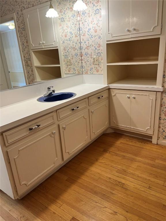 620 S Summit St, Iowa City, IA 52240 - kitchen with wallpapered walls, open shelves, a sink, light wood-style flooring, and light countertops