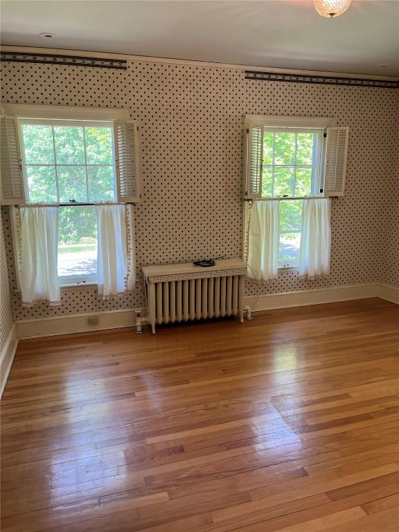 620 S Summit St, Iowa City, IA 52240 - empty room with radiator, baseboards, healthy amount of natural light, light wood finished floors, and wallpapered walls
