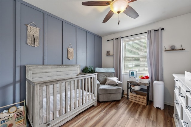 1500 Rock Island Dr, Ely, IA 52227 - bedroom featuring a nursery area, wood finished floors, and ceiling fan