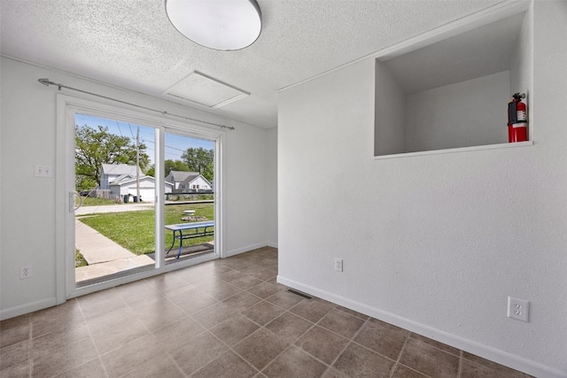 1337 Ellis Blvd NW, Cedar Rapids, IA 52405 - spare room featuring attic access, a textured ceiling, baseboards, and tile patterned flooring