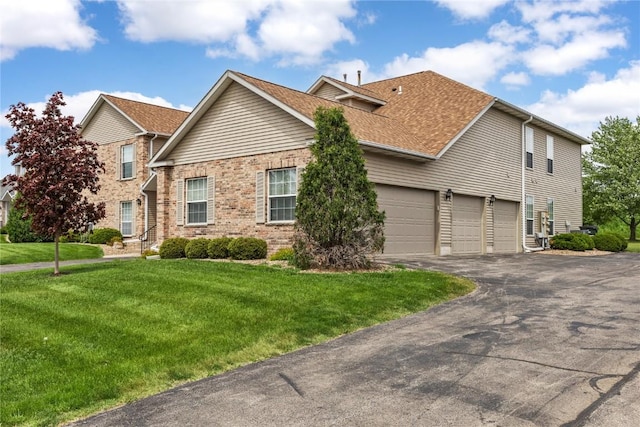 3110 Towne House Dr NE Unit C, Cedar Rapids, IA 52402 - view of front of property featuring driveway, a front lawn, brick siding, a garage, and roof with shingles