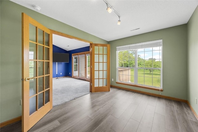 3110 Towne House Dr NE Unit C, Cedar Rapids, IA 52402 - empty room with french doors, wood finished floors, baseboards, rail lighting, and lofted ceiling