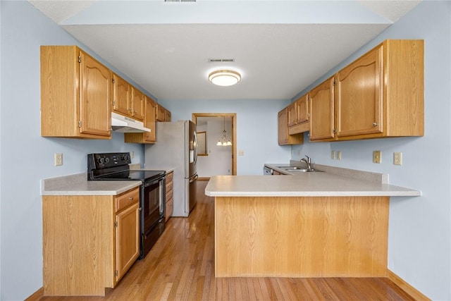 3110 Towne House Dr NE Unit C, Cedar Rapids, IA 52402 - kitchen featuring black range with electric stovetop, a sink, under cabinet range hood, a peninsula, and light countertops