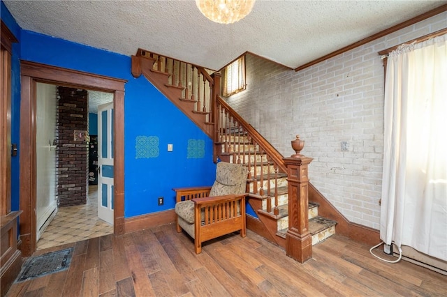 3136 155th St, Muscatine, IA 52761 - stairway with wood-type flooring, brick wall, baseboards, and a textured ceiling