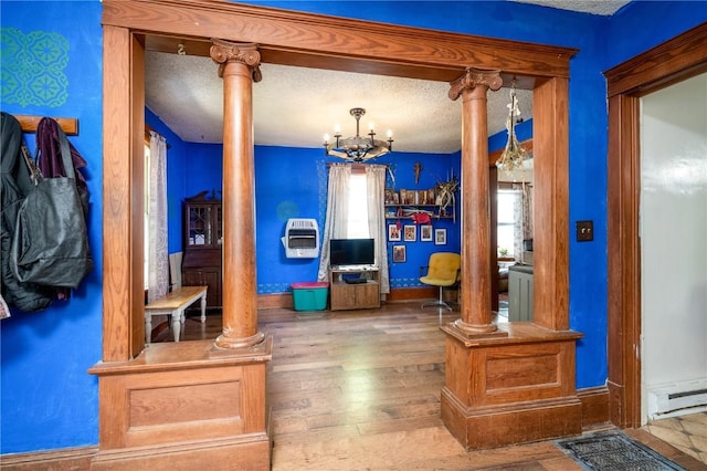 3136 155th St, Muscatine, IA 52761 - living room featuring ornate columns, a baseboard heating unit, hardwood / wood-style floors, heating unit, and a textured ceiling