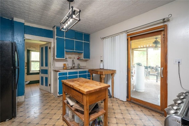 3136 155th St, Muscatine, IA 52761 - kitchen with freestanding refrigerator, blue cabinetry, a sink, light countertops, and an ornate ceiling