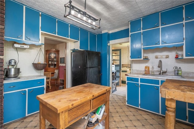 3136 155th St, Muscatine, IA 52761 - kitchen featuring a sink, blue cabinetry, freestanding refrigerator, backsplash, and an ornate ceiling