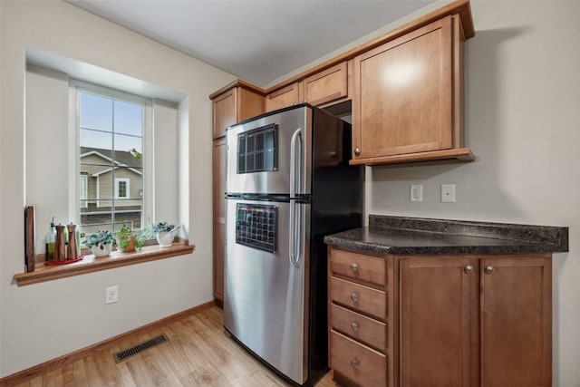 1075 Twilight Dr, North Liberty, IA 52317 - kitchen featuring freestanding refrigerator, light wood-style floors, dark countertops, brown cabinets, and baseboards
