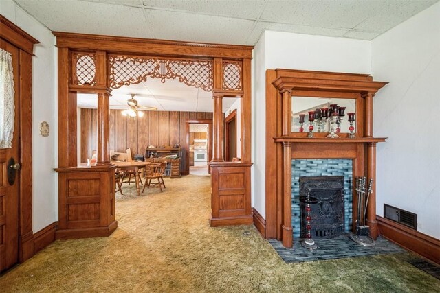 205 2nd Ave, Atkins, IA 52206 - living room with carpet floors, wood walls, ceiling fan, a tiled fireplace, and a desk